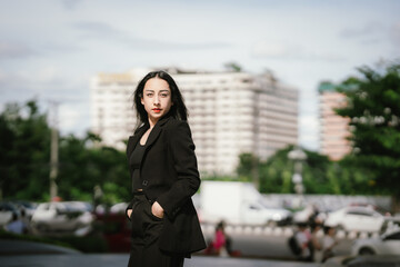 Fototapeta premium A confident, stylish woman in a black blazer walks through the city with coffee and smartphone in hand, embodying modern ambition, elegance, independence, and professional success. 