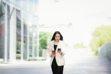 A businesswoman in a chic white blazer and holding a cup of coffee represents modern elegance,...