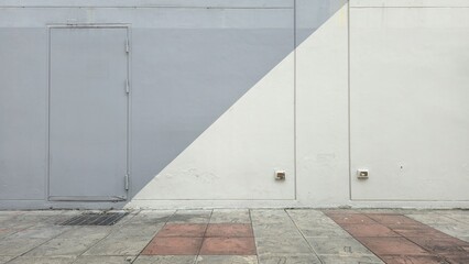 The building's storage room door, gray and white painted cement walls, red and gray tiled floors, and the back entrance door to the building.