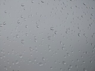Raindrops on glass creating a textured view of a gray sky during a rainy day