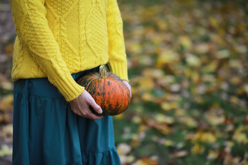 Woman Holding Pumpkin in Autumn Park with Yellow Sweater and Green Dress