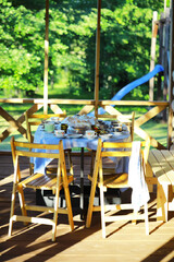 Sunny Outdoor Breakfast Setting with Wooden Chairs and Picnic Table in Green Garden