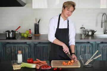 Asian cook in the kitchen prepares food in a cook suit
