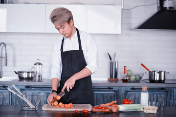 Asian cook in the kitchen prepares food in a cook suit