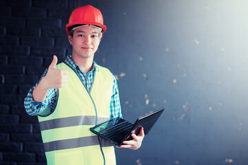 Asian man in protective helmet and construction waistcoat