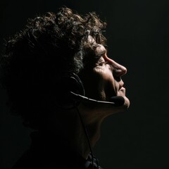 A man with curly hair, wearing a headset that includes a microphone