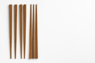 Wooden chopsticks arranged on a white surface with room for text or ads, highlighting Asian culinary traditions.
