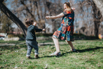 A colorful candid moment between a mother and child in a grassy park, waving sticks in the spring...