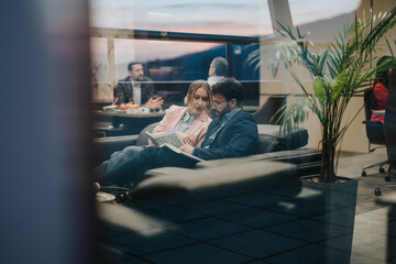 A man and a woman in business attire are conversing and collaborating in a comfortable office...