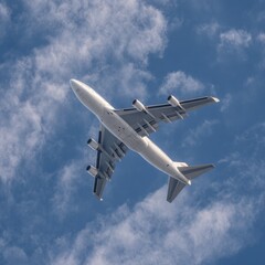 Obraz premium Large white airplane high above puffy clouds