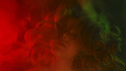 Artistic portrait of girl behind colored glass with dramatic lighting