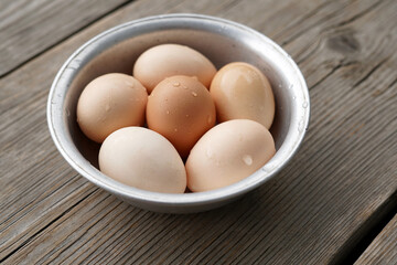 Closeup Free Range Eggs in Various Shades in Metal Bowl on Wooden Background. Farming.             ...