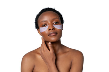 Woman applying skincare treatment with under-eye patches in a minimalistic setting during a beauty routine
