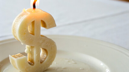 Climate Economic Risk A dollar sign candle flickers on a plate, symbolizing money and celebration.