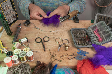 Man making trout flies. Fly tying equipment and material for fly fishing preparation .
