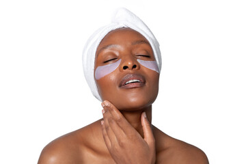 Woman enjoying a relaxing skincare treatment with under-eye patches while wrapped in a towel in a...