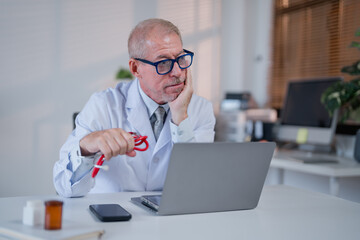 Medical professional working late at healthcare facility shows signs of fatigue while sitting at...