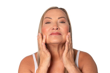 Woman with long hair applying skincare on her face in a bright studio environment during daytime