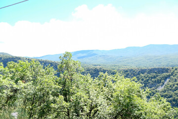 Expansive panoramic view of rolling green hills and forests under a clear sky, typical of the natural beauty found near Pescasseroli in Abruzzo, Italy.