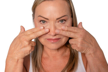 Woman demonstrating facial skincare techniques at home during the day while smiling and showcasing...