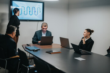 Group of colleagues discussing a project during a corporate meeting. Attendees include men and...