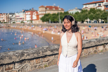copyspace Young woman enjoying music walking near the beach in summer