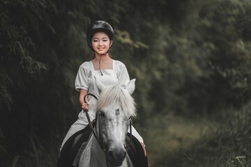 Young Woman Riding Horse in Lush Green Forest Pathway