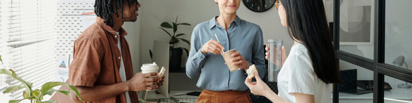 Colleagues having a coffee break and discussing in a modern office