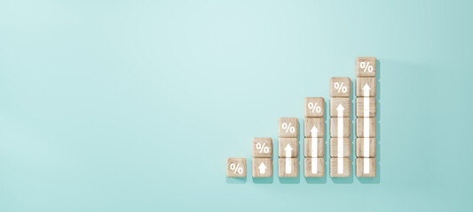 Wooden blocks with percent signs and upward arrows arranged as ascending bar chart on blue...