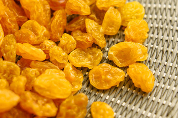 Dried dehydrated yellow raisins on wicker green kitchen mat. Top view. 