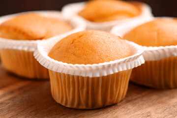 Group of fresh baked vanilla cupcakes in paper cups on wooden table. 