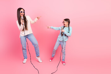 Mother and daughter enjoying a fun karaoke time together wearing sunglasses and showcasing their...