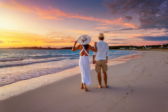 A romantic honeymoon couple stands on a tropical paradise beach and enjoys the beautiful sunrise, Bahamas, Caribbean islands - Powered by Adobe