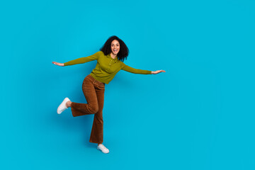 Young woman in casual colorful outfit posing playfully on blue background showcasing vibrant energy...