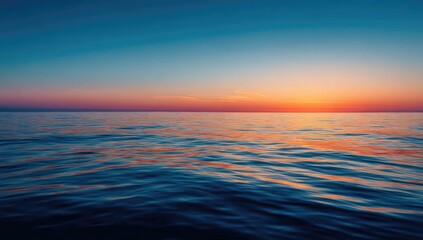 Serene ocean sunset with calm waves reflecting vibrant orange, pink, and blue hues across the water's surface