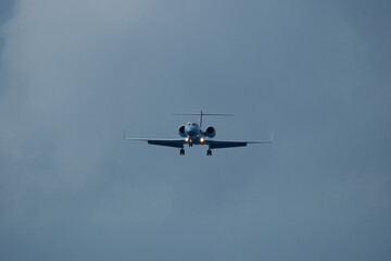 Private jet approaching the airport. Airplane in the cloudy sky.