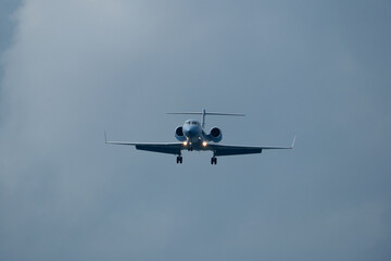 Private jet approaching the airport. Airplane in the cloudy sky.