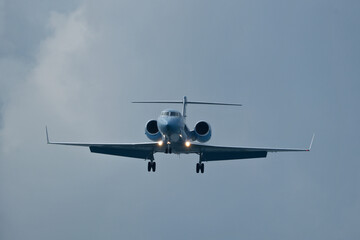 Private jet approaching the airport. Airplane in the cloudy sky.