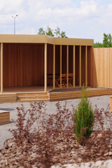 modern wooden gazebo exterior with minimalistic design on sunny day surrounded by garden plants and...