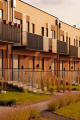 modern townhouse architecture featuring brown facades and metal balconies in suburban neighborhood....