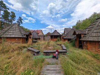 Opuszczony skansen wiejski – drewniane chaty i dzika roślinność © smoku7979