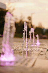 illuminated fountains with pink lights create enchanting patterns at sunset. captivating urban...