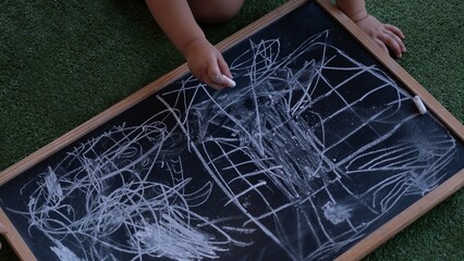 Child drawing with chalk on blackboard