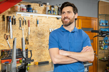 Man mechanic posing with arms crossed in garage for skilled worker portrait