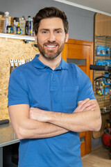 Bearded man mechanic standing with arms crossed in workshop