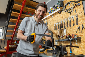 Velomechanic in professional attire servicing bicycle with specialized tools in workshop setting