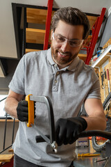 Bike mechanic in workwear using tools to repair bicycle