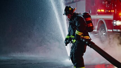 Firefighter battles flames with powerful hose during night rescue operation in city