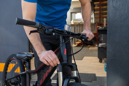 Man adjusts the handlebars of mountain bike inside workshop