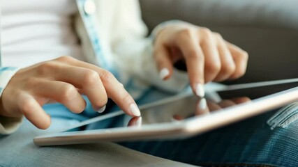 Close-up of a young woman using a tablet for digital messaging. Her fingers are tapping on the screen, showcasing mobile communication. - Powered by Adobe